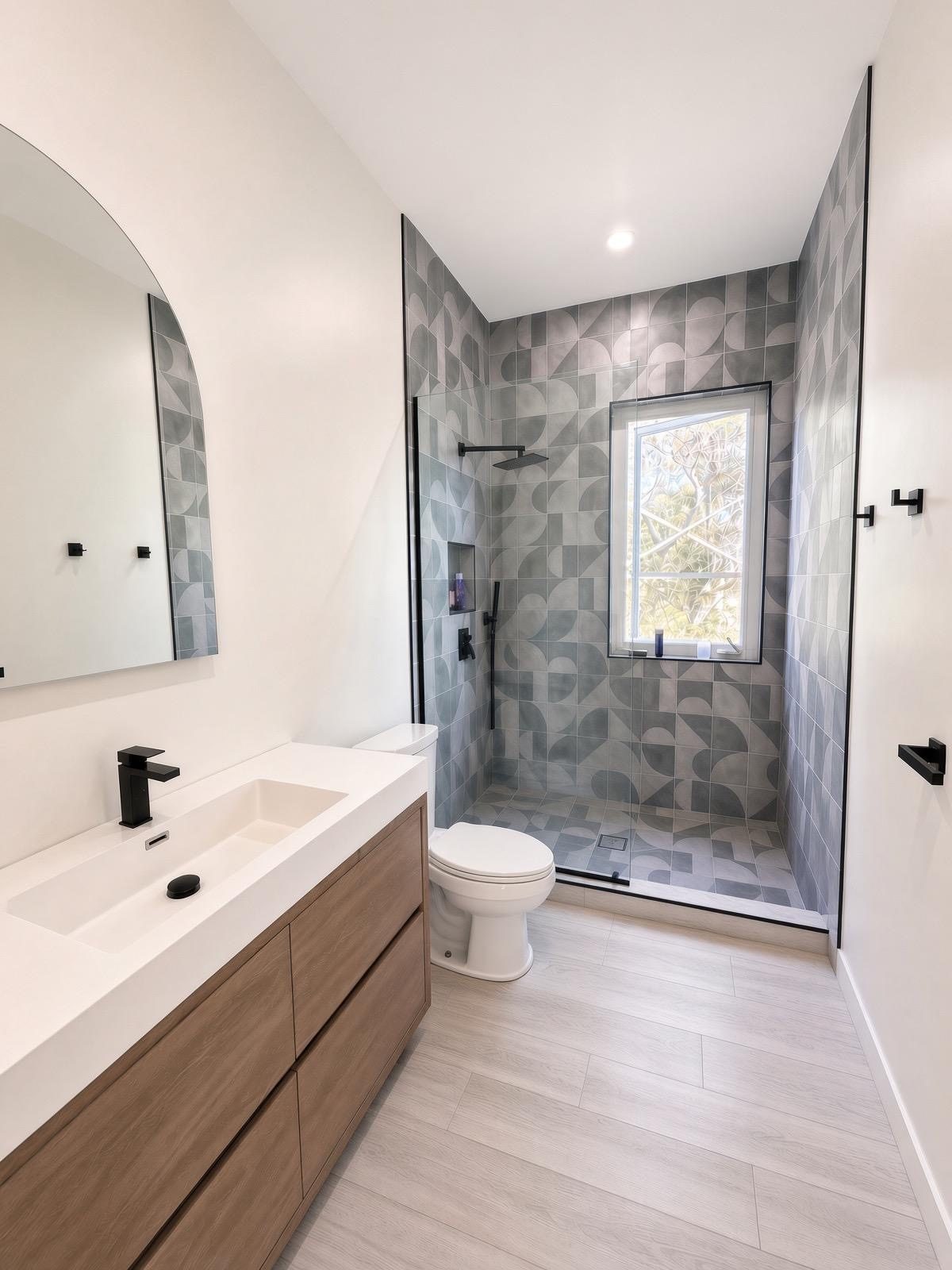 Bathroom with patterned tile walk in shower and black fittings